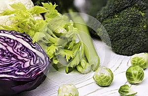 A close-up of the harvest of fresh vegetables on a wooden table: cabbage, broccoli, and Brussels sprouts and red cabbage