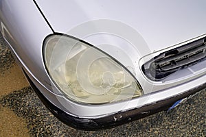 Close up hazy yellowed dirty car unpolished cloudy foggy front plastic automobile headlight worn