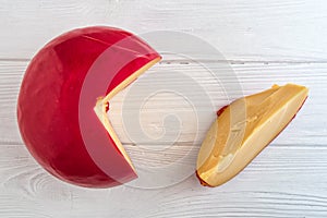 Close up. Head of Dutch cheese Edam and sliced piece on white wooden background