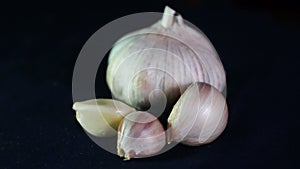 Close-up of the head of garlic, and slices on a dark surface. Macro