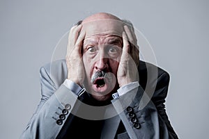 Close up head portrait of bald 60s senior business man surprised and scared looking as if big mistake or disaster in the office photo