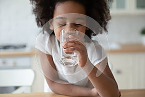 Close up head shot African American little girl drinking water