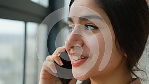 Close up head shot Arabian girl talking mobile phone near window smiling female businesswoman lady speak business call
