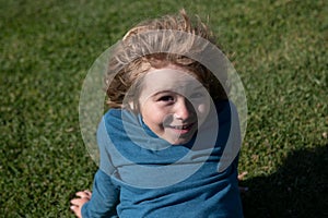 Close up head shot of child on grass in park. Kids funny face, little boy portrait.