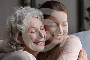 Close up head shot devoted old mother cuddling grownup daughter.