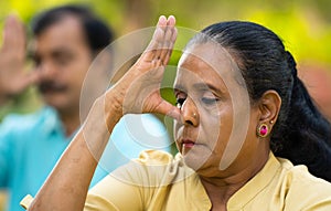 Close up head shot of elderly Indian senior woman doing nostril breathing yoga or pranayama exercise - concept of zen