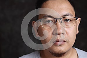 Close up head shot portrait of Asian man wearing glasses looking at camera