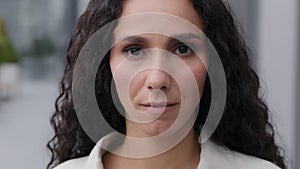 Close up head shot portrait outdoors 30s beautiful calm serious sad upset woman look at camera outdoors. Gorgeous female