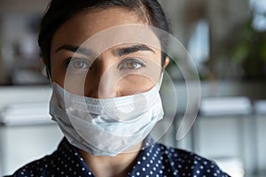 Serious cautious indian ethnic woman in protective medical mask. photo