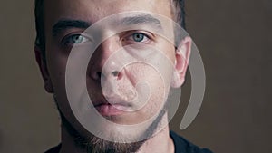 Close-up head shot portrait young serious handsome european appearance man. Young millennial bearded man open his blue