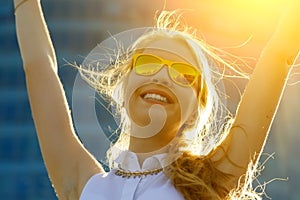 Close up head shot portrait of young woman with arms raised rejoicing summer