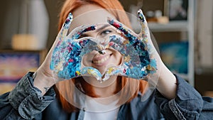 Close up head shot red-haired 20s smiling girl in eyeglasses smiling toothy friendly with love painter woman looking at