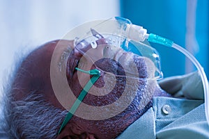Close up head shot side view of old man breathing with ventilator oxygen mask at hospital due to coronavirus covid-19 lung