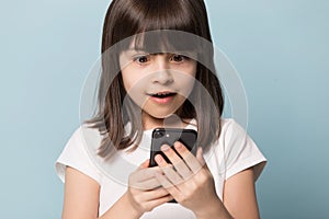 Close up excited preschool girl holding mobile phone.