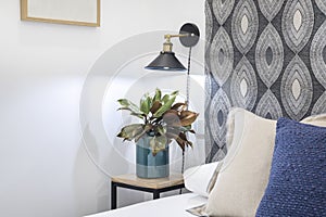 Close-up of headboard decorating the bedside table with a blue vase with plant and vintage lamp