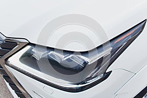 Close up of headlight detail of modern luxury car with projector lens for low and high beam. Front view of sport