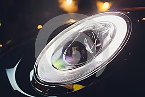 Close up of headlight detail of modern luxury car with projector lens for low and high beam. Front view of sport