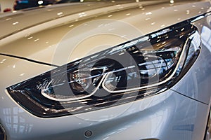 Close up of headlight detail of modern luxury car with projector lens for low and high beam. Front view of sport