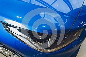 Close up of headlight detail of modern luxury car with projector lens for low and high beam. Front view of sport