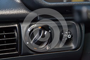 Close-up on the headlight switch control buttons and automatic adjust level dashboard in retro old car in the vehicle repair