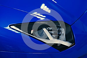 Close-up of the headlights of a blue sports car in a showroom or garage