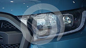 Close up of headlights of modern car model in dealer centre on trading platform