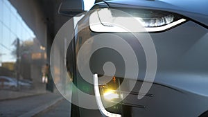 Close up of headlights of modern car. Switching of automobile LED head lights. New auto headlamp. Front of vehicle with