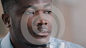 Close up headshot african millennial man drink pure fresh cold water glass healthy liquid suffer from hot make daily