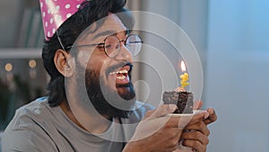 Close up headshot arabic spanish bearded male portrait happy indian birthday man in festive cap on head making wish