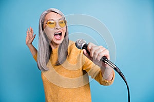 Close-up headshot photo of charming lovely singer old lady holding microphone open mouth close eyes singing last high