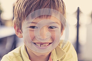 Close up headshot portrait of young little 7 or 8 years old boy with sweet funny teeth smiling happy and cheerful in joy face expr