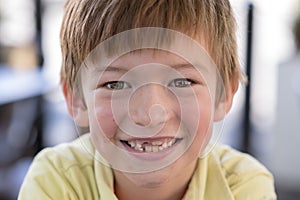 Close up headshot portrait of young little 7 or 8 years old boy with sweet funny teeth smiling happy and cheerful in joy face expr