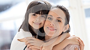 Close up headshot portrait young single happy mommy embracing daughter.
