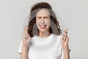 Close up headshot portrait young superstitious woman crossing fingers.