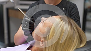 Close-up headshot of pretty blonde female patient sitting in stomatology seat with open mouth during unrecognizable