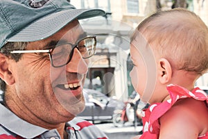 Close-up headshot of a white Caucasian mature father grandfather playing with a cute baby girl toddler