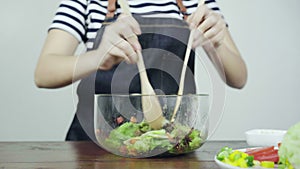 Close up of Health conscious young chief woman tossing a tasty organic green salad