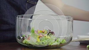 Close up of Health conscious young chief woman tossing a tasty organic green salad
