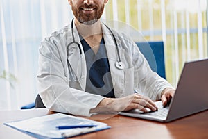 Close up of healthcare worker with stethoscope using laptop while working at doctor& x27;s office