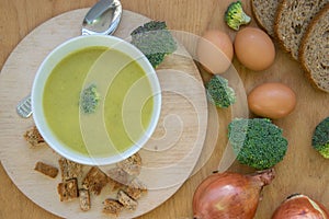 Close-up of healthy lunch, vegetable soup from broccoli, and bread, onion, eggs in the back, food on a wooden table, healthy