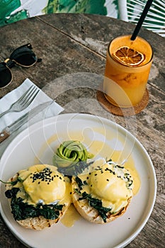 Close up Healthy sandwiches Breakfast with Bread Toast and Poached Egg with spinach, avocado on wooden table. Orange