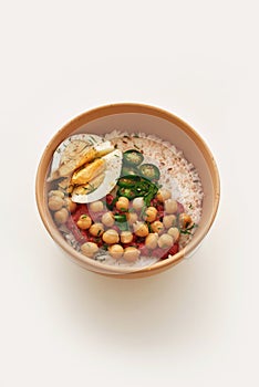 Close up of healthy vegetable bowl lunch with egg, rice, chili pepper, hummus and beans isolated over white background