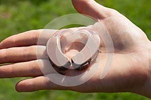 Close up of hearing aids in heart shape on hand with a natural green background