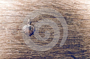 Close up of heart locket on wooden background with retro style