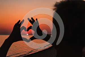 Close up of heart made by female hands background the sunset sea. Vintage effect style pictures.