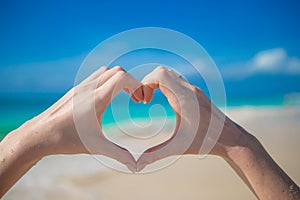 Close up of heart made by female hands background the turquoise ocean