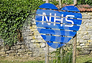 Close up of heart made of wood painted blue with the letters NHS in white. photo