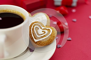 Close up heart shape ginger bread, cookie. Cup of coffee, morning drink. Red background with copy space