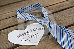 Close up of heart shape paper with text by necktie on table