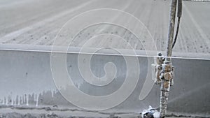 Close-up of heavy road construction machine spraying water onto edge of concrete highway